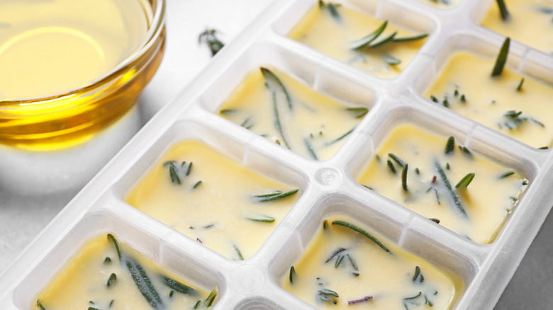 an ice cube tray with leftover herbs frozen in oil