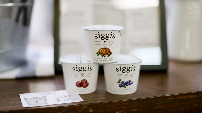 Three Siggi's fruit yogurts stacked on wooden table