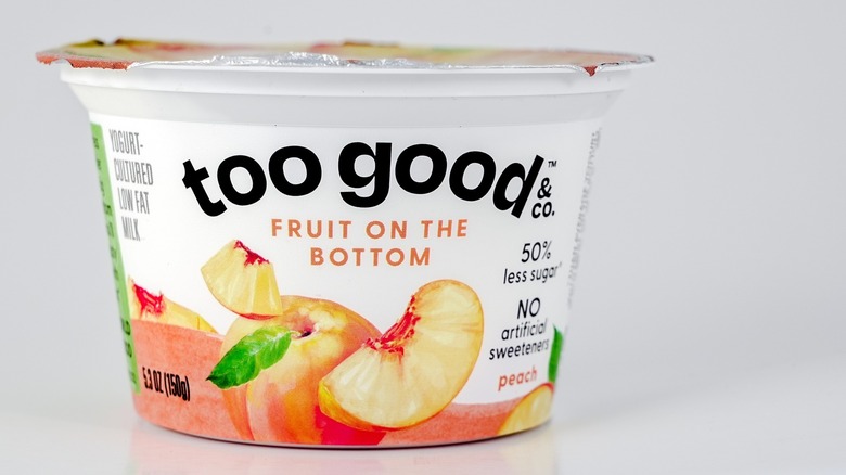 A tub of peach yogurt on a white background