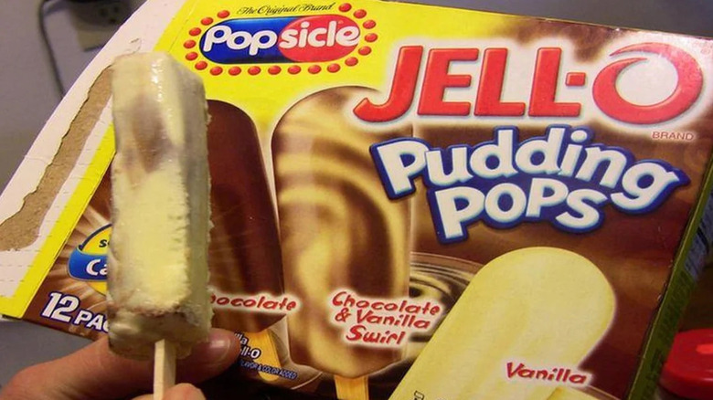 Someone holding an open Jell-O pudding pop in front of the packaging