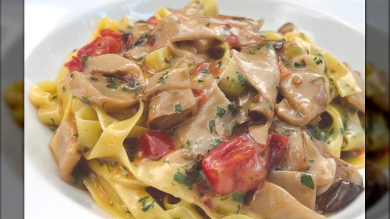 A bowl pasta with tomatoes and mushrooms.