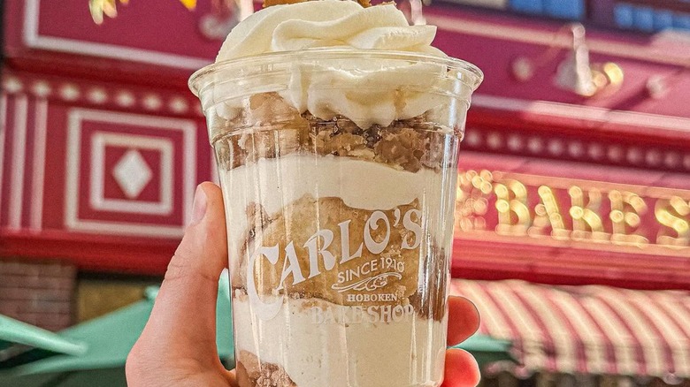 Someone holding a Carlo's Bakery milkshake in front of the bakery.