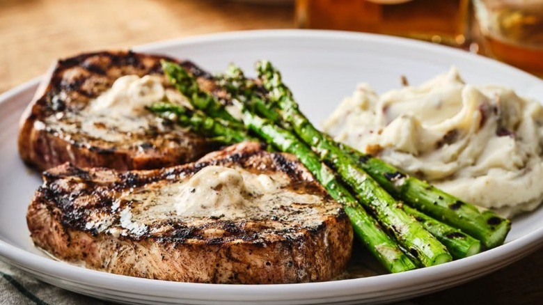 A plate holding two pork chops, asparagus, and mashed potatoes.