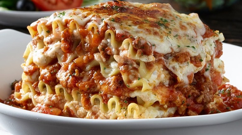A very large lasagna portion on a white plate.