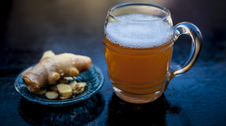 Ginger on a plate beside a glass mug of ginger beer