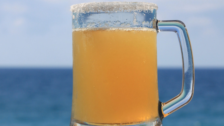 Glass of beer with salt on the rim with sea and sky in background