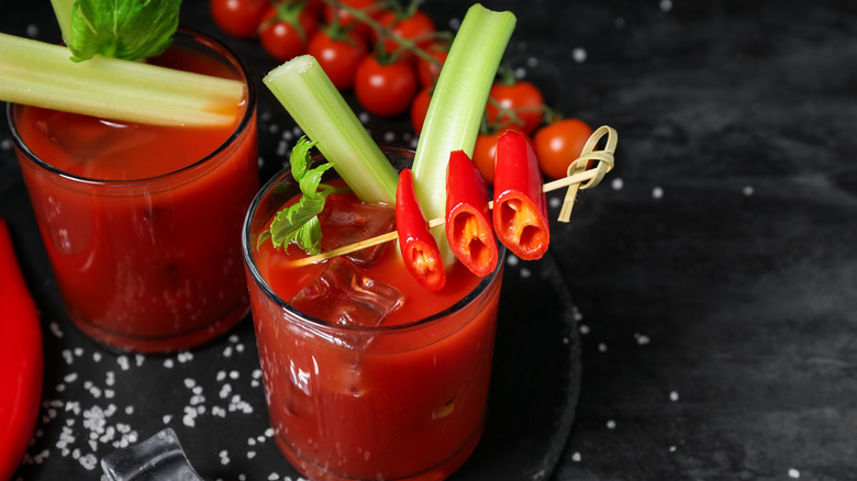 Two bloody mary drinks on a black surface