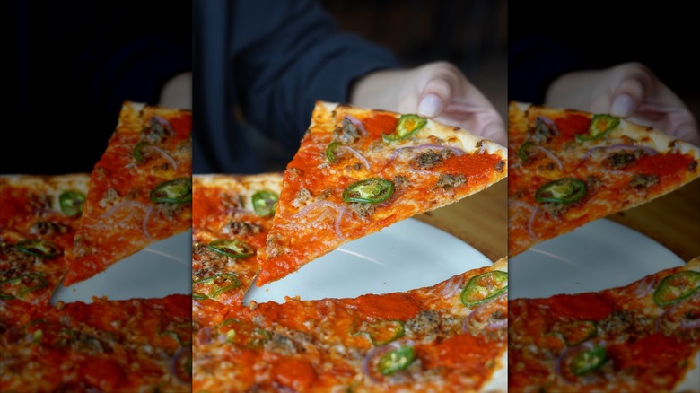 Slice of pizza pulled from a whole pie