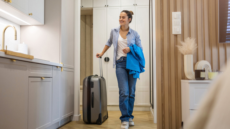 Woman entering rented apartment with luggage