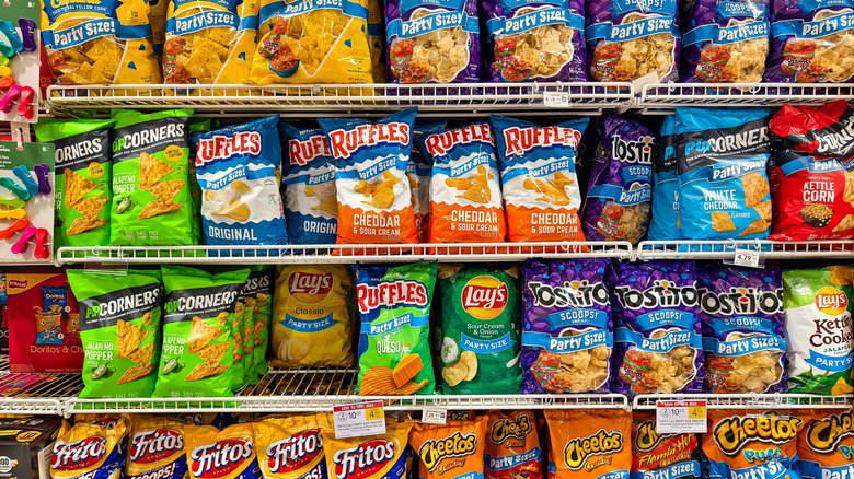 A wide assortment of potato chips and snacks from Frito-Lay displayed on shelves in a supermarket aisle