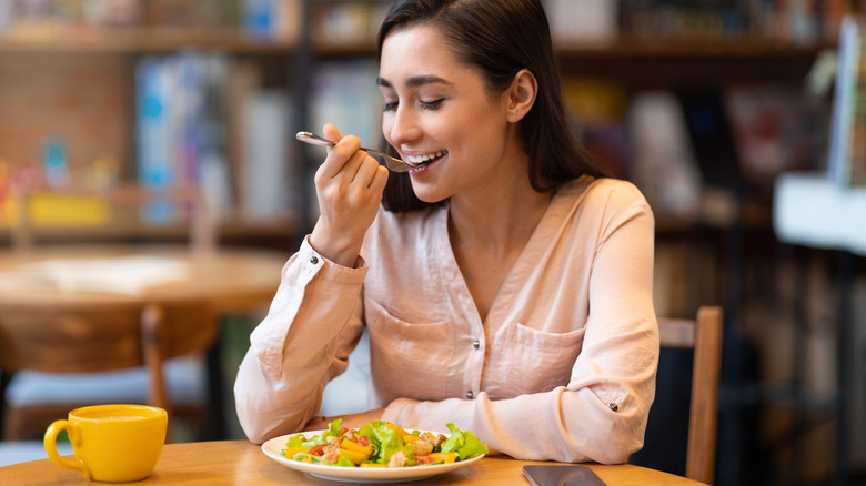 Woman eating healthy meal, sitting indoors in restaurant
