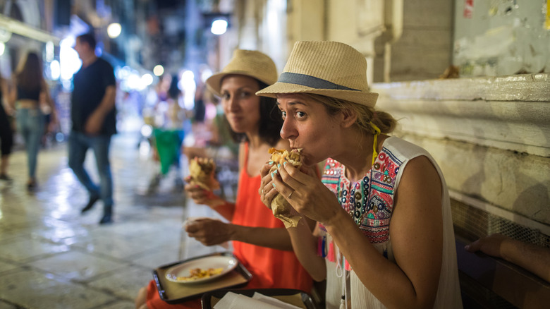 Two hungry women eating street food on summer holiday