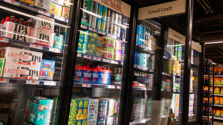 Canned beer in a supermarket cool a man looks over the brands
