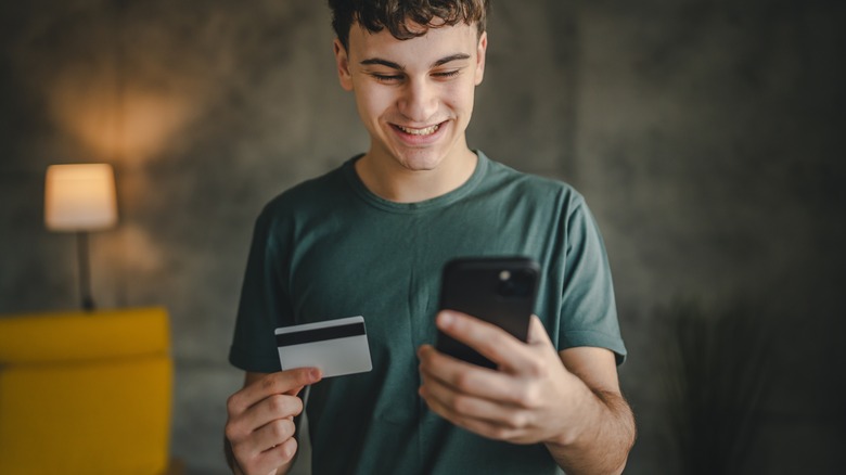 smiling man holding cell phone and credit card