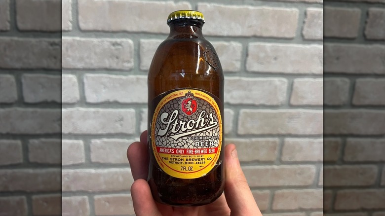 Hand holding up a bottle of Stroh's