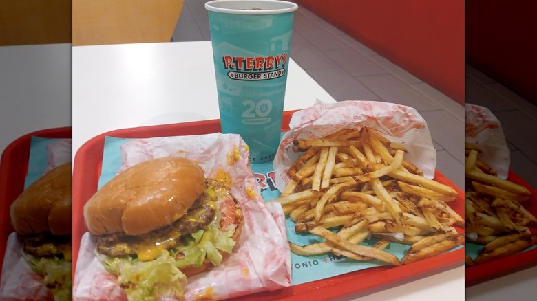 A red tray holding a cheeseburger, fries, and a drink from P. Terry's.