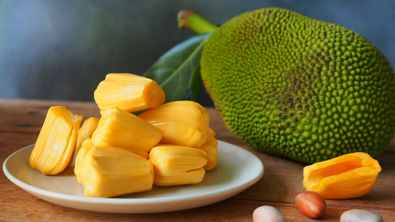 Ripe jackfruit flesh on white plate on wooden table