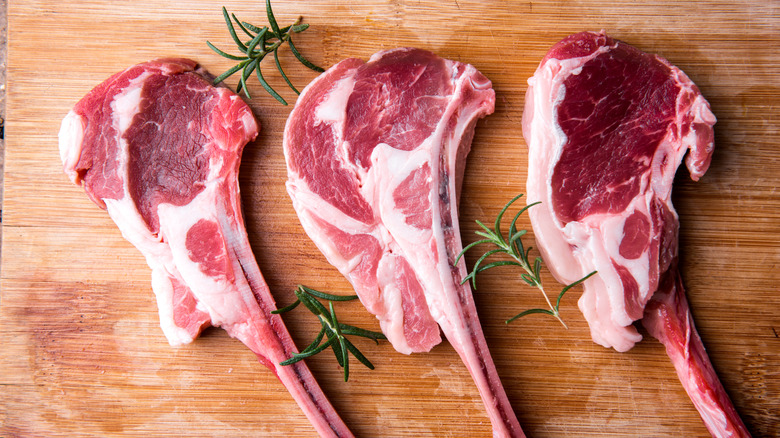 Raw lamb chops and fresh rosemary on a wood board