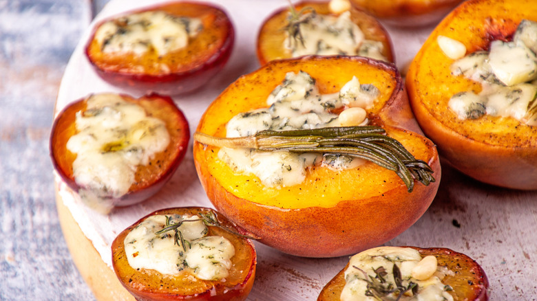 Filled baked peaches with rosemary and cheese on wooden serving plate