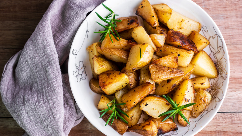 A bowl of roasted potatoes and fresh rosemary