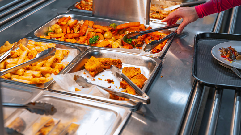 woman using tongs at buffet line