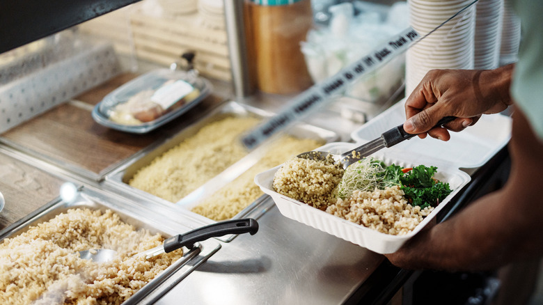 man packing food to go from buffet