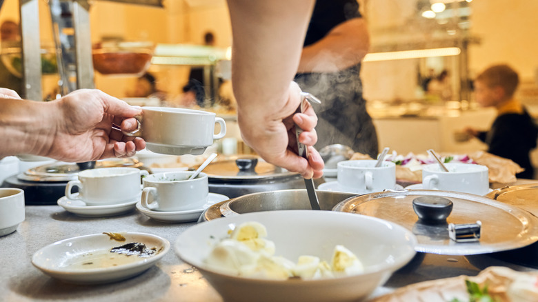 person dipping up soup from buffet line