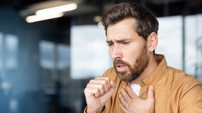 man coughing into fist