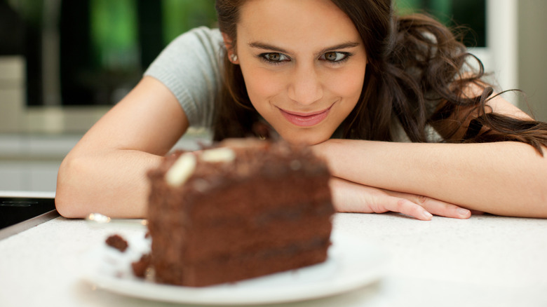 woman smiling at a plate of chocolate cake