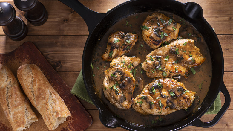 chicken in black skillet with mushrooms and parsley