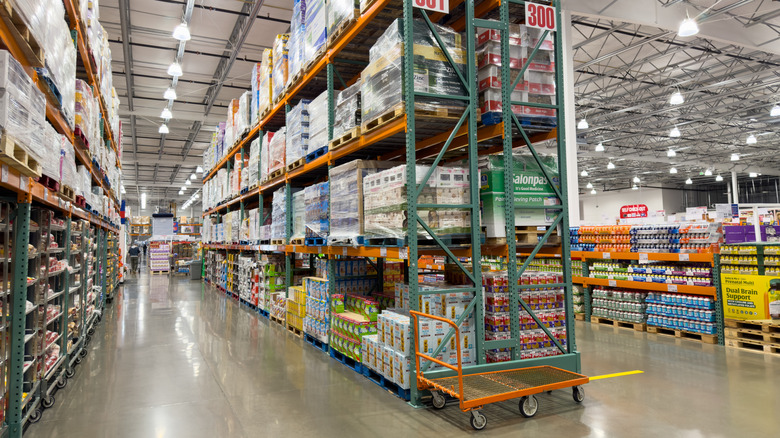 Towering Costco warehouse shelves in aisle full of various bulk products.