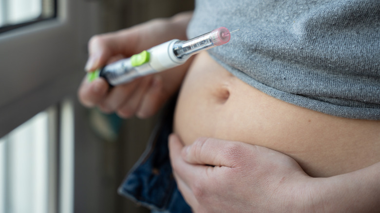 A pregnant woman prepares to inject herself with an IVF fertility drug.