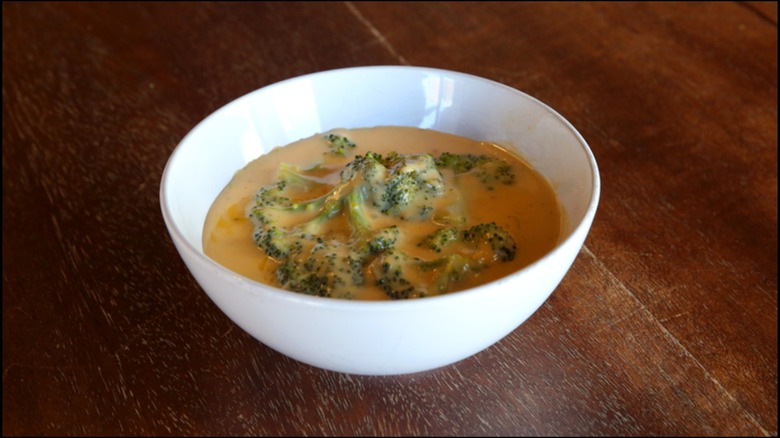 Bowl of broccoli cheese soup on wooden table