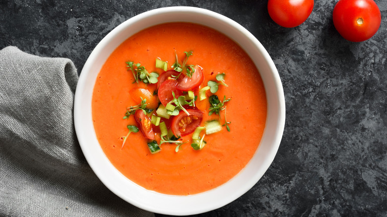 Bowl of gazpacho topped with fresh herbs and diced tomatoes
