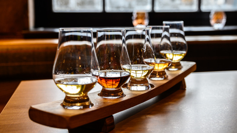 Whiskey flight of five glasses on wooden board
