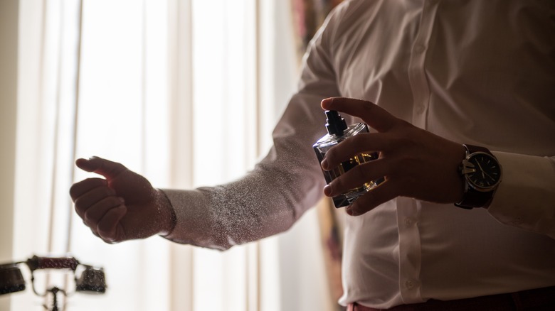 Man spraying cologne onto wrist