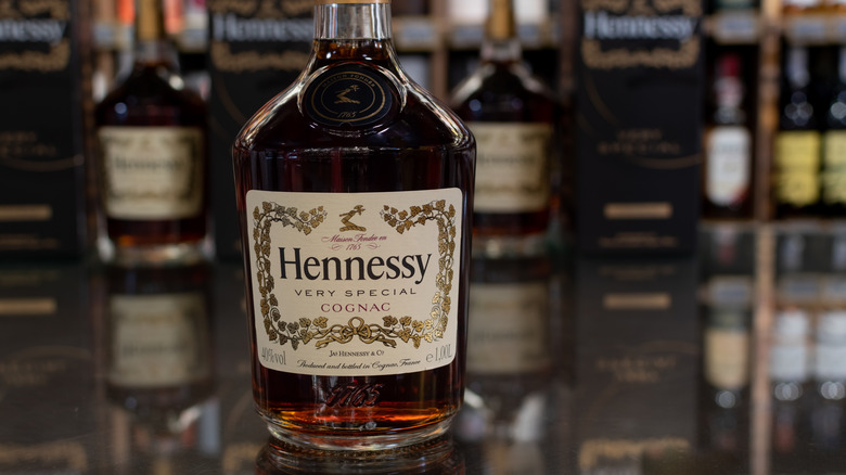 A bottle of Hennessy VS Cognac in front of several other bottles of Hennessy in the background