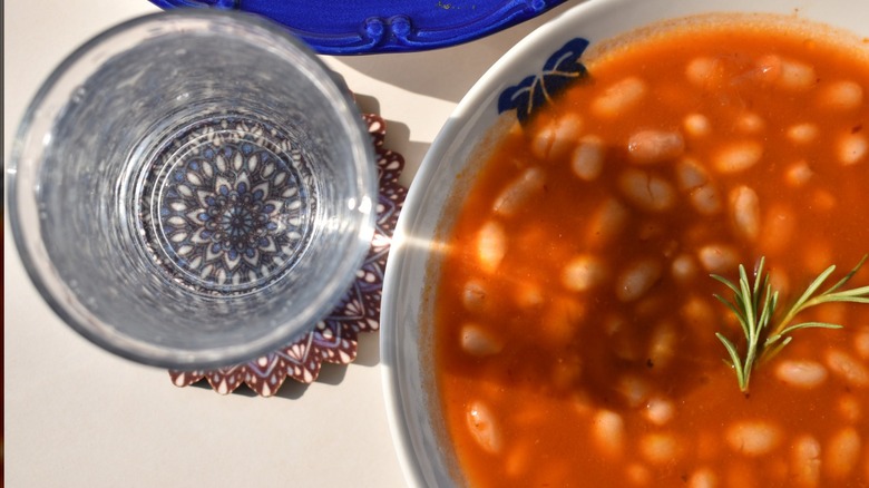 Baked bean soup closeup in a bowl with a glass cup in aerial view
