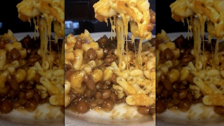 Mac and cheese with baked beans combined on paper plate