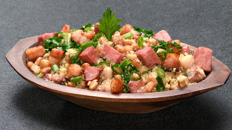 Sausage and beans in an oval shaped wooden bowl topped with parsley and green onion
