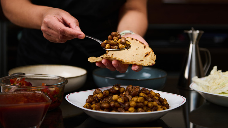 Person spooning beans onto taco shells