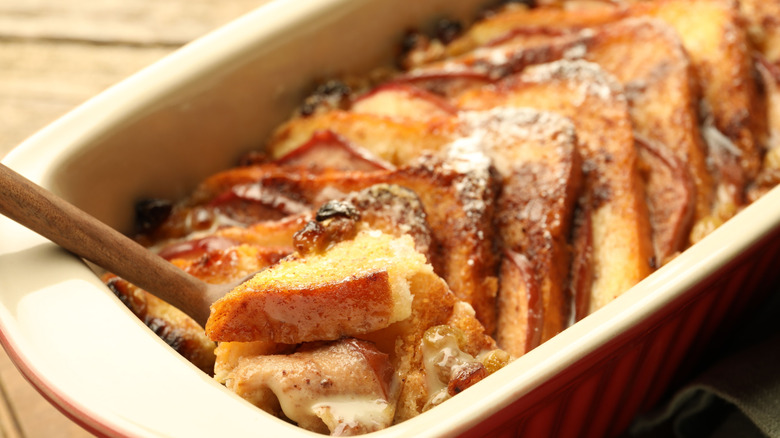 A tray of bread pudding with a wooden spoon.