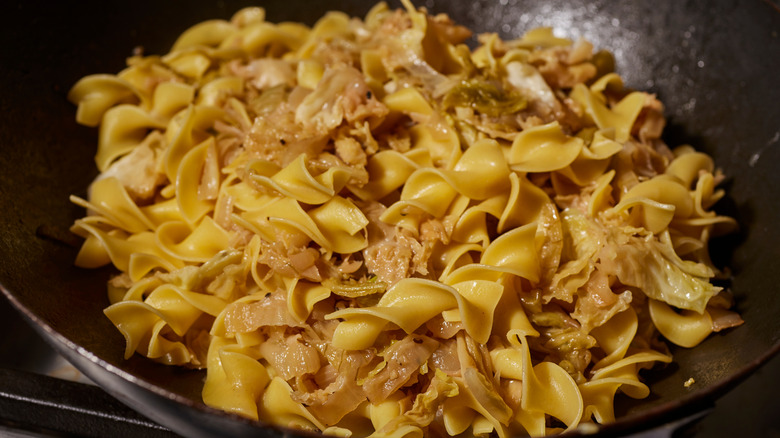 A skillet full of noodles and meat.