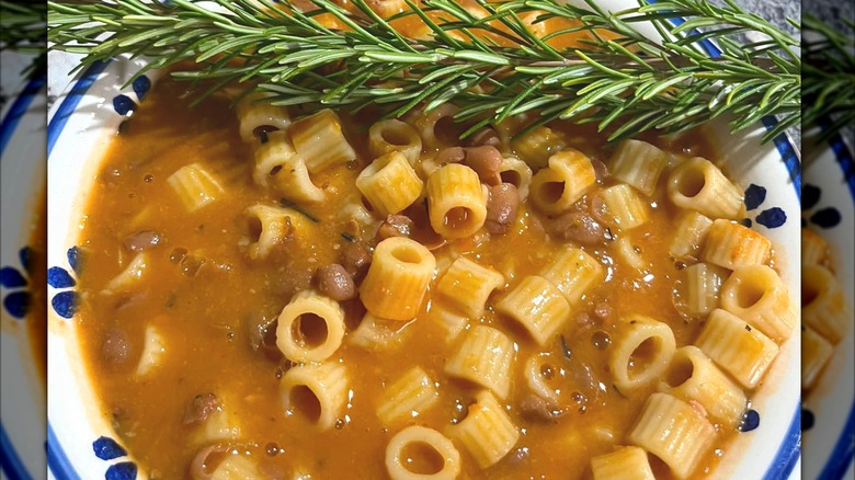 A sprig of thyme resting on top of a bowl of Pasta e Fagioli
