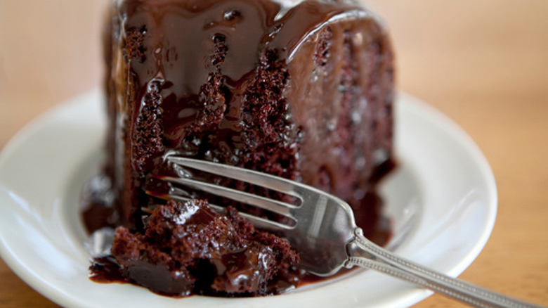 A fork cutting into a thick slice of frosted chocolate cake.