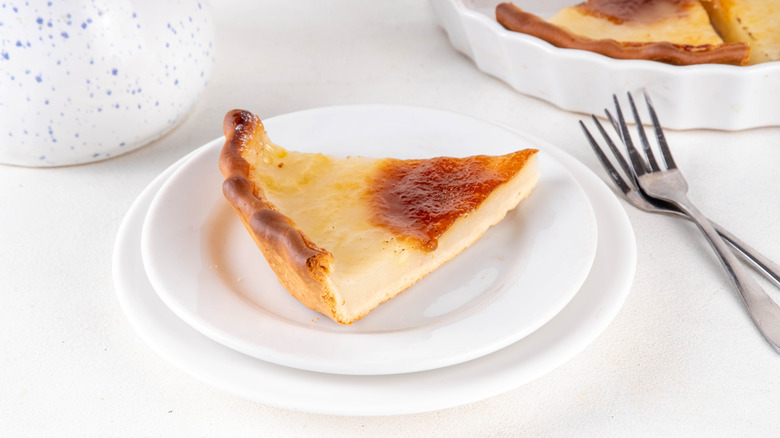 A slice of water pie on a plate next to forks and the rest of the pie.