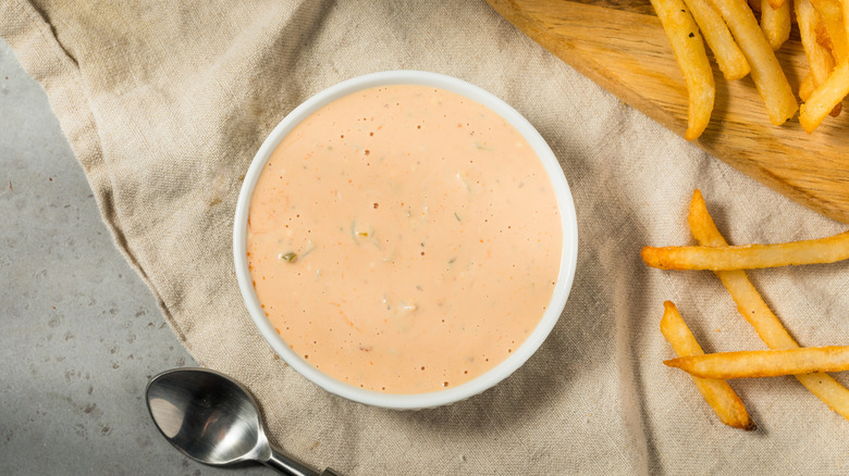 Comeback sauce in large white ramekin by fries and spoon