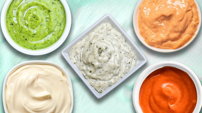 Five different kinds of mayonnaise in white tubs