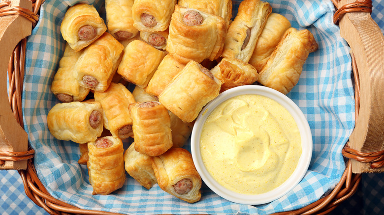 Pigs in a blanket and Joppie sauce ramekin in picnic basket