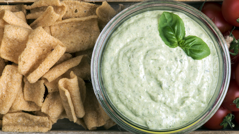 Green mayo in bowl by loose chips